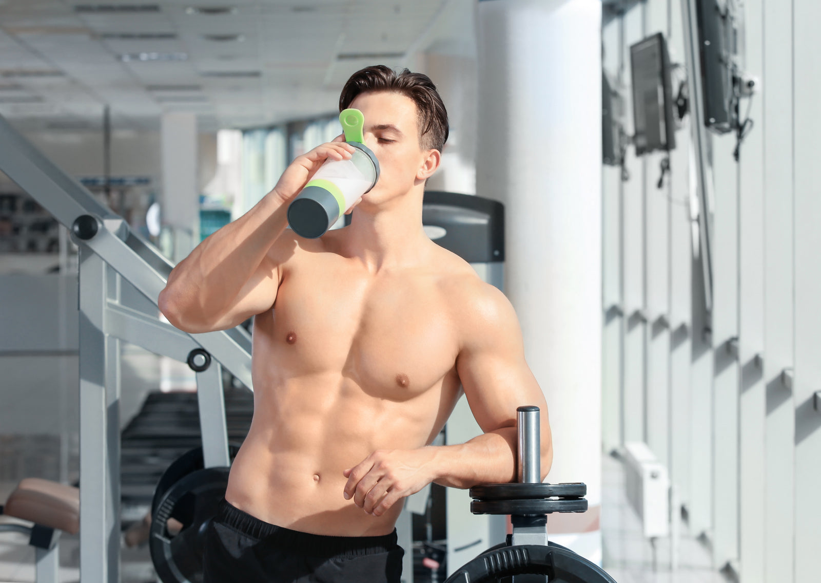 Spor salonunda shaker'dan içecek içen sporcu