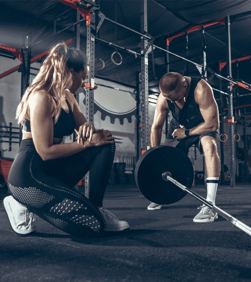 Spor salonunda halter ağırlığı hazırlayan iki sporcu