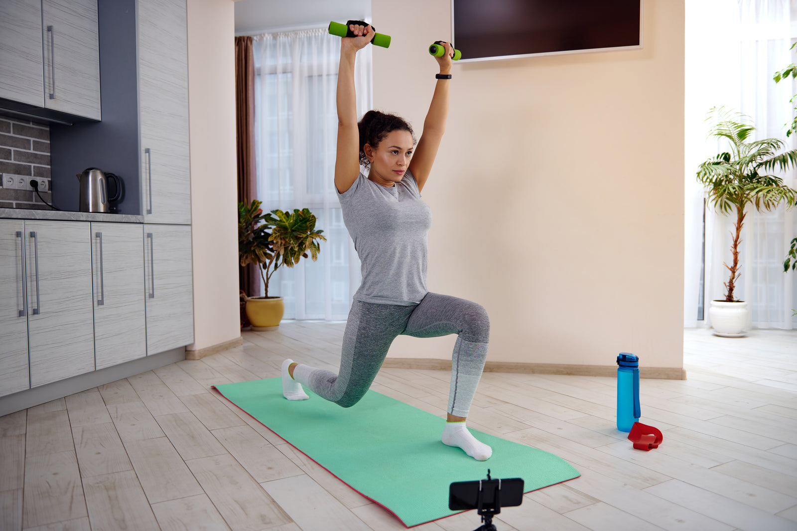 Matta dumbbell ile lunge çalışan kişi