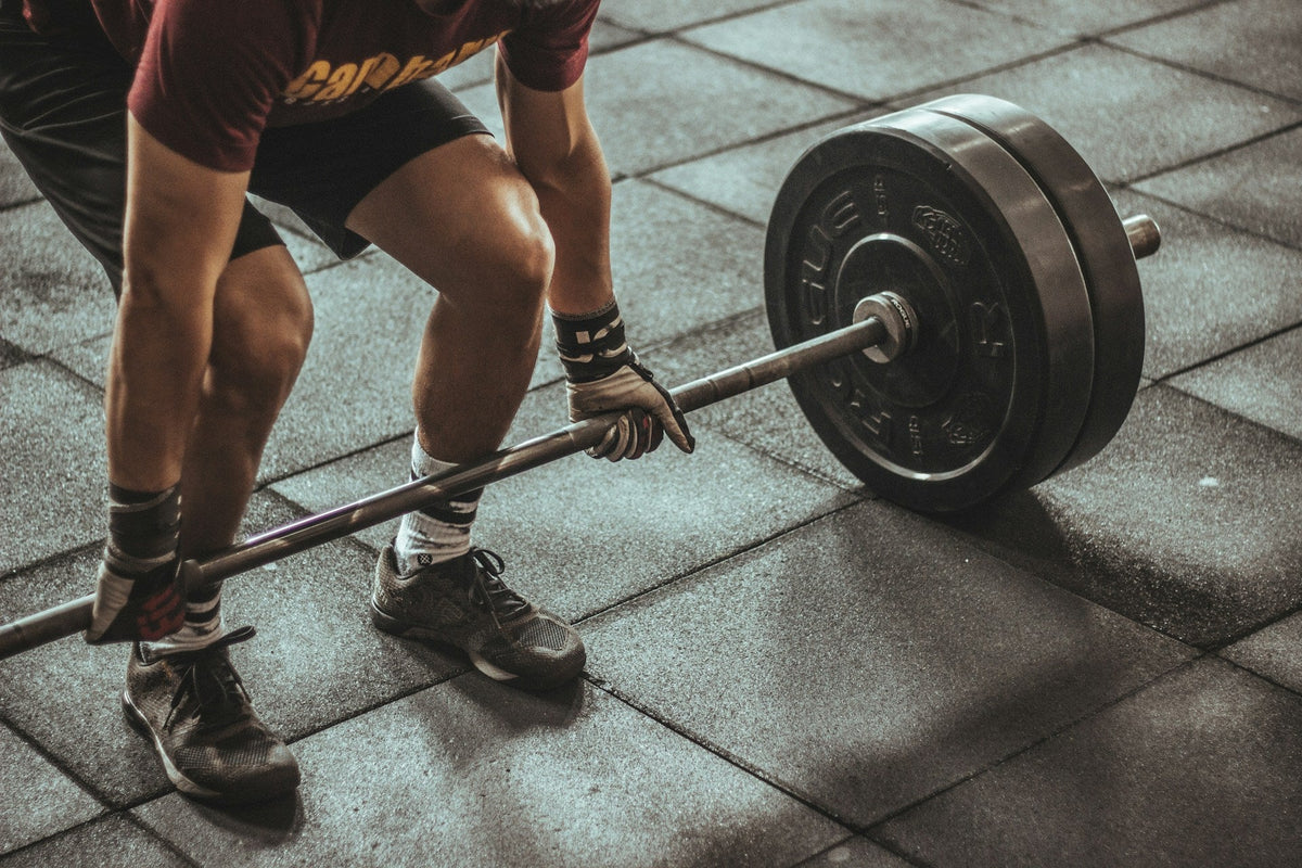 Spor salonunda yerden halter kaldırmaya hazırlanan sporcu